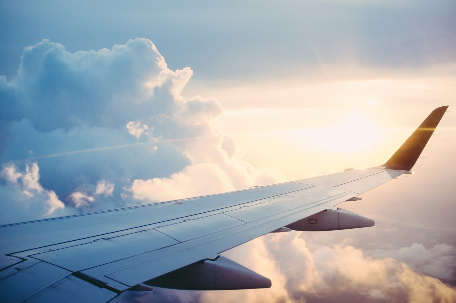 Une aile d’avion au-dessus des nuages au soleil couchant